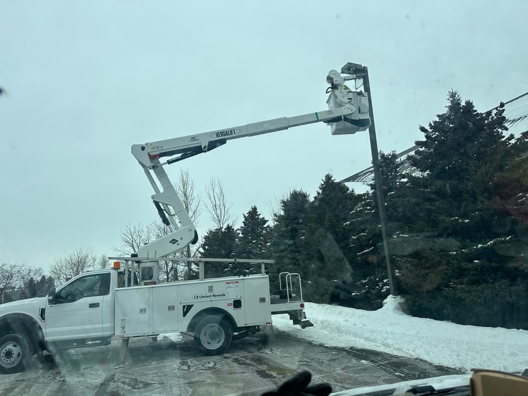 picture of a commercial project parking lot lights maintained by master electrician in a bucket truck