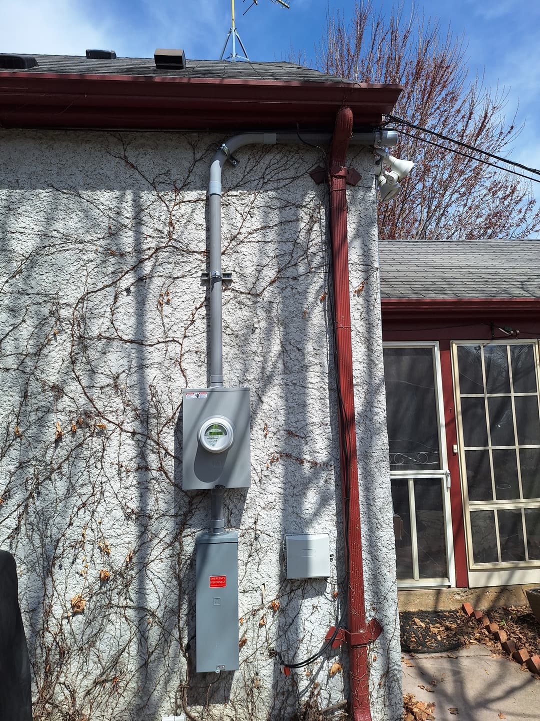 Updated exterior electric meter and service disconnect installed on stucco wall.