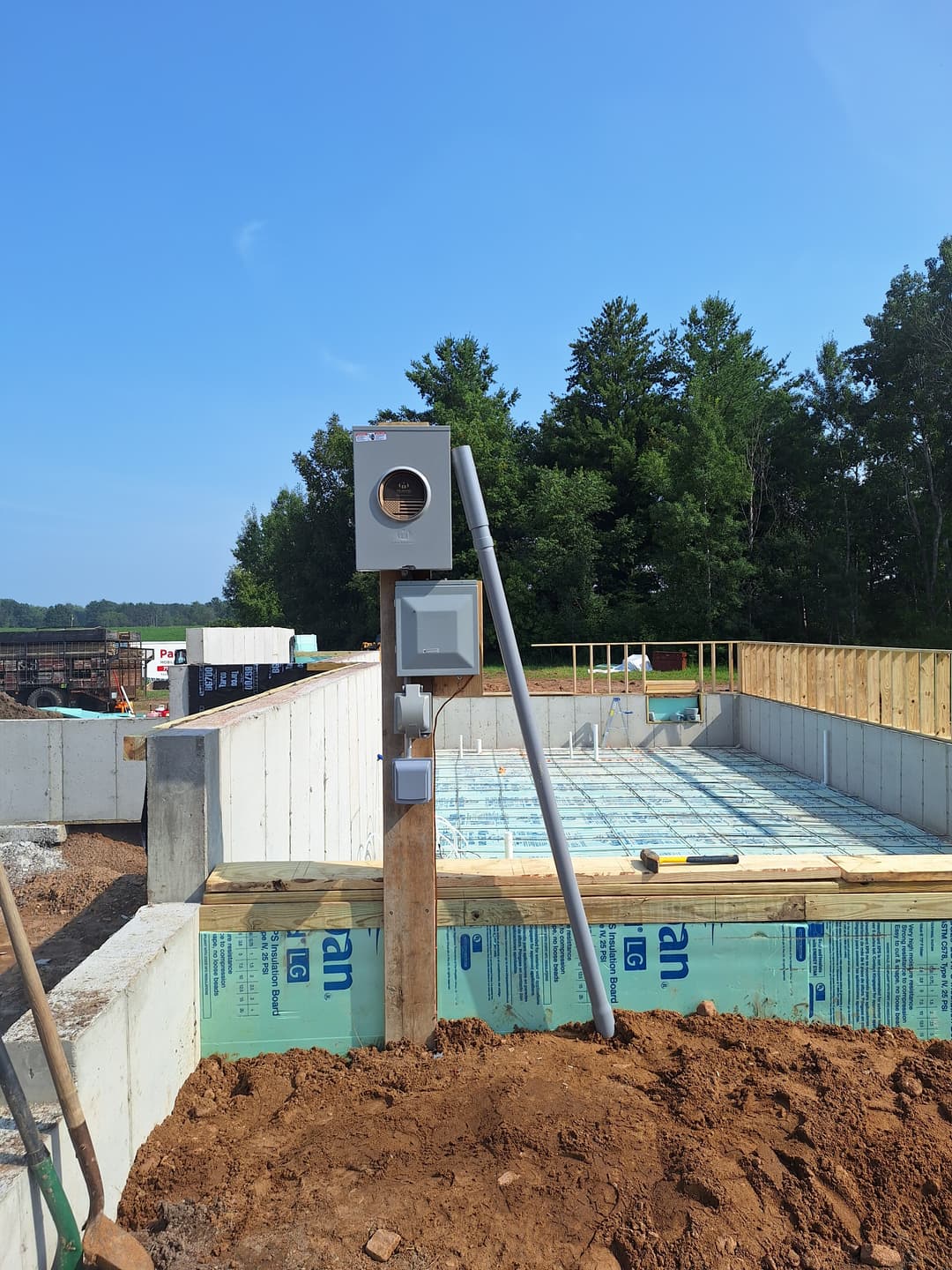 Temporary electrical meter and service installation on a construction site foundation.
