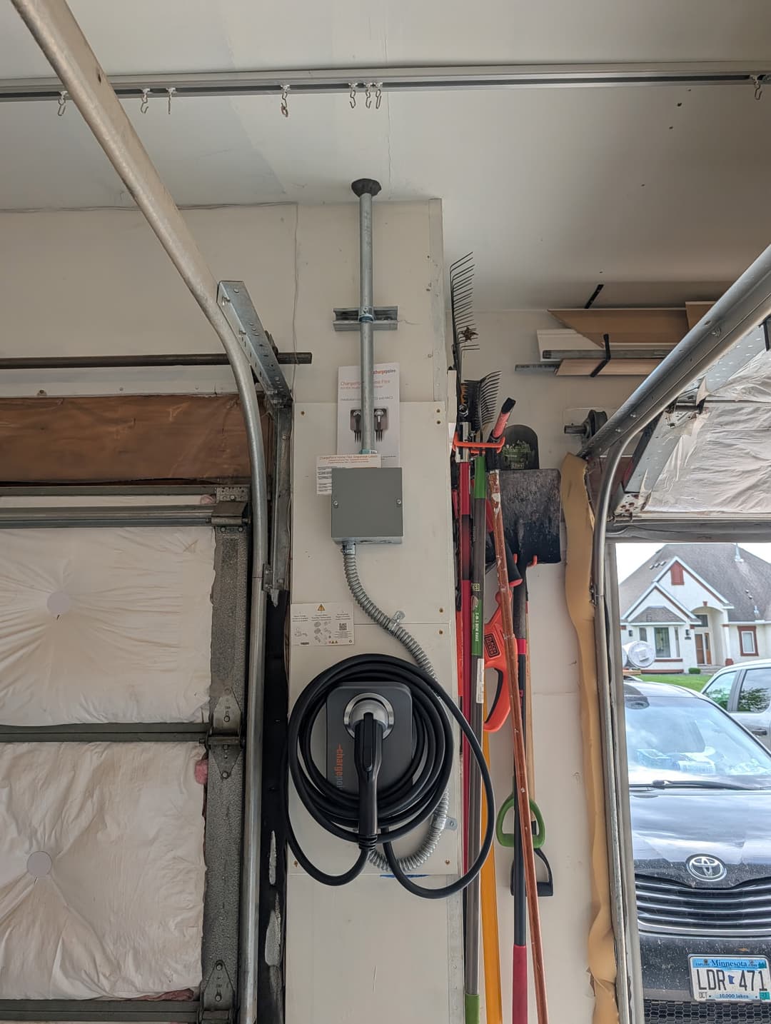 ChargePoint EV charger wall-mounted in a residential garage with conduit routed to the ceiling for a new car-charging installation.