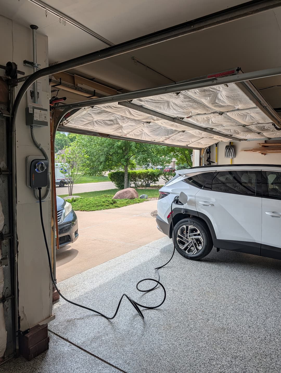 ChargePoint Level 2 EV charger plugged into a white SUV in a residential garage.