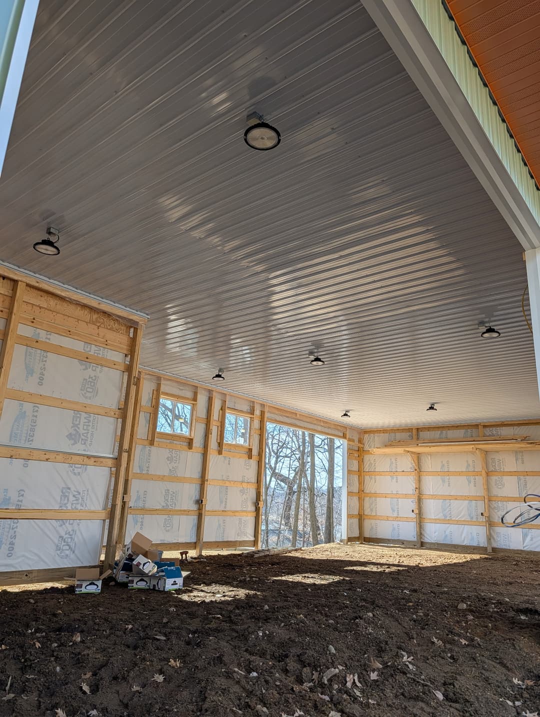 LED high-bay lights installed in the vaulted ceiling of a pole building under construction.
