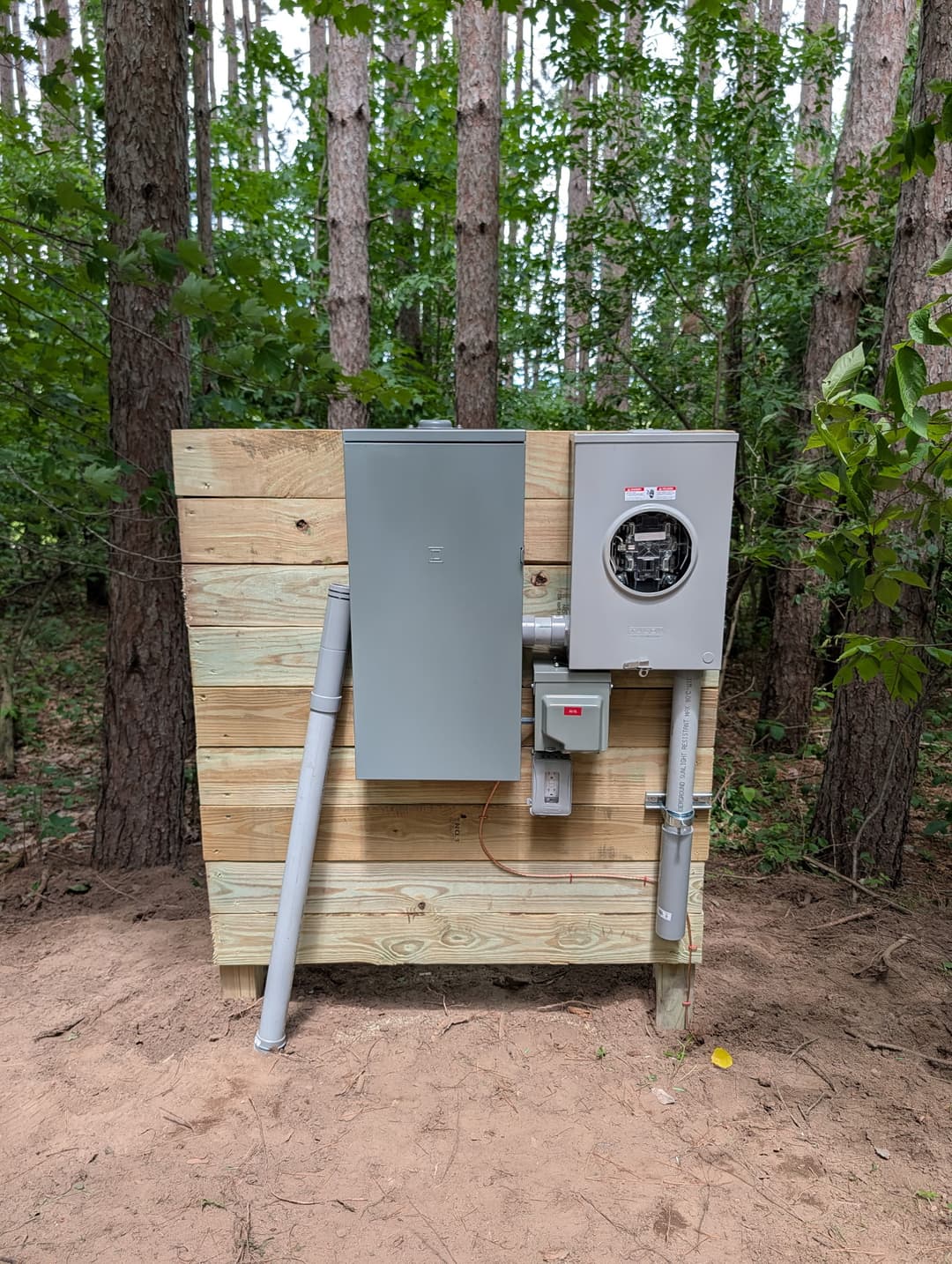 Meter socket and Square D panel mounted on a wood post stand for new electrical service in a rural field.
