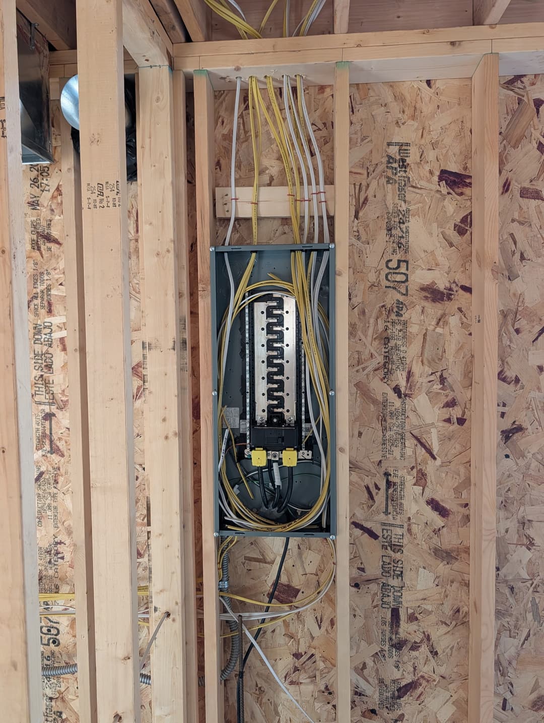 200A panel with organized wiring installed inside a framed wall during new home construction.