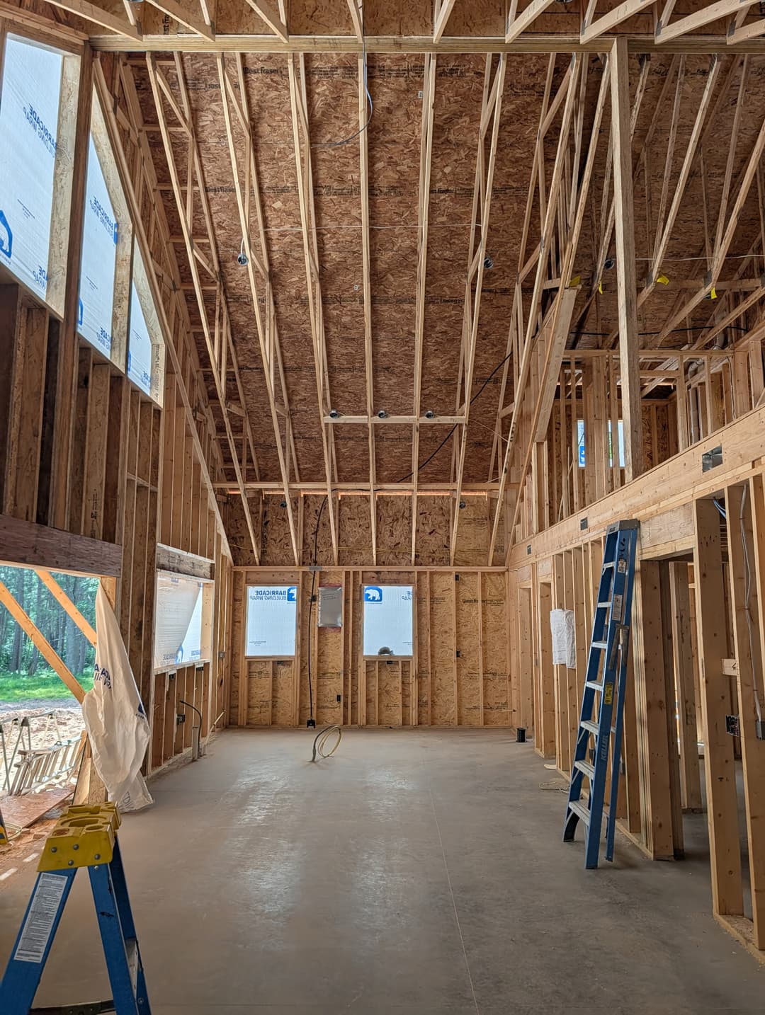 Recessed lighting wire drops installed in the vaulted ceiling of a great room under construction.