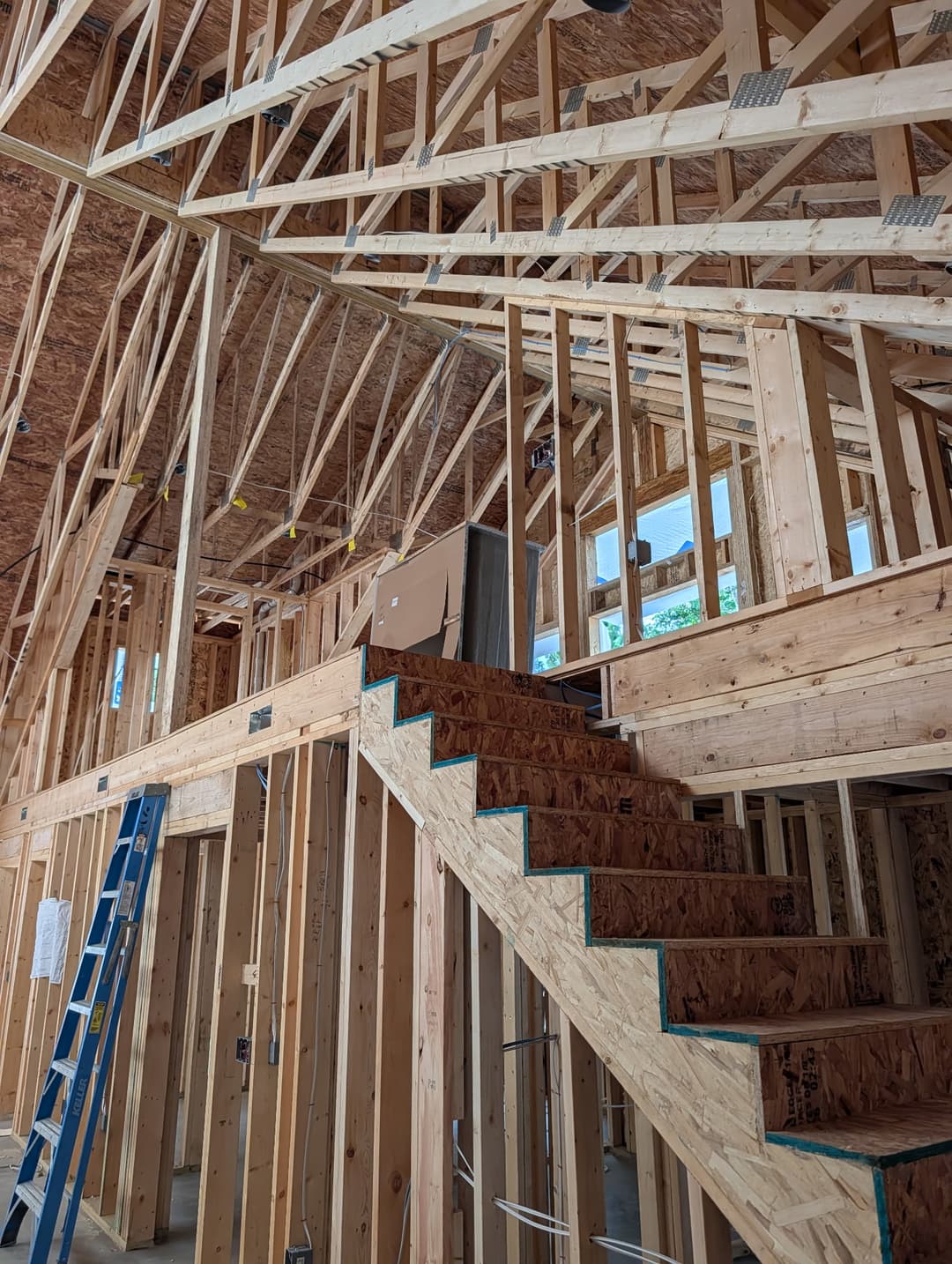 Recessed lighting wiring installed above an open staircase in a two-story home under construction.