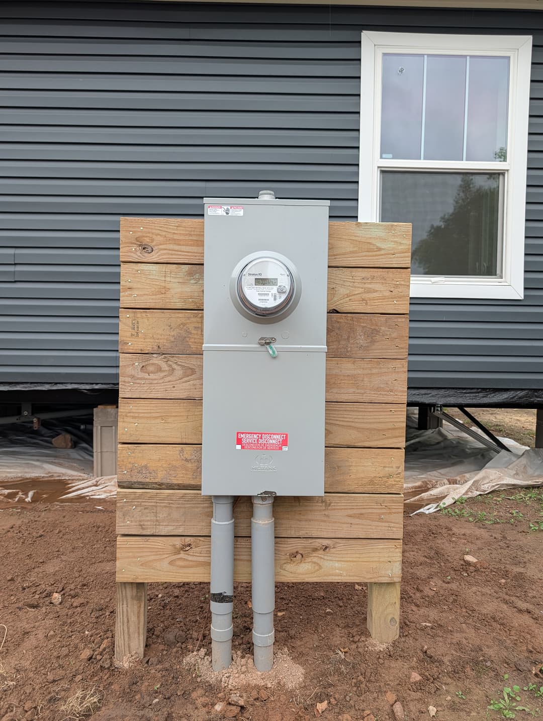 Outdoor electric meter and service disconnect mounted on a wooden post with conduit below.