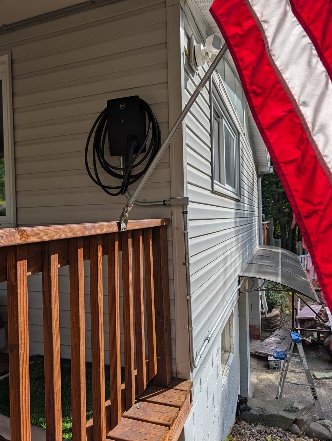 GM Energy Level 2 EV charger wall-mounted near a deck with conduit routed to the electrical panel.