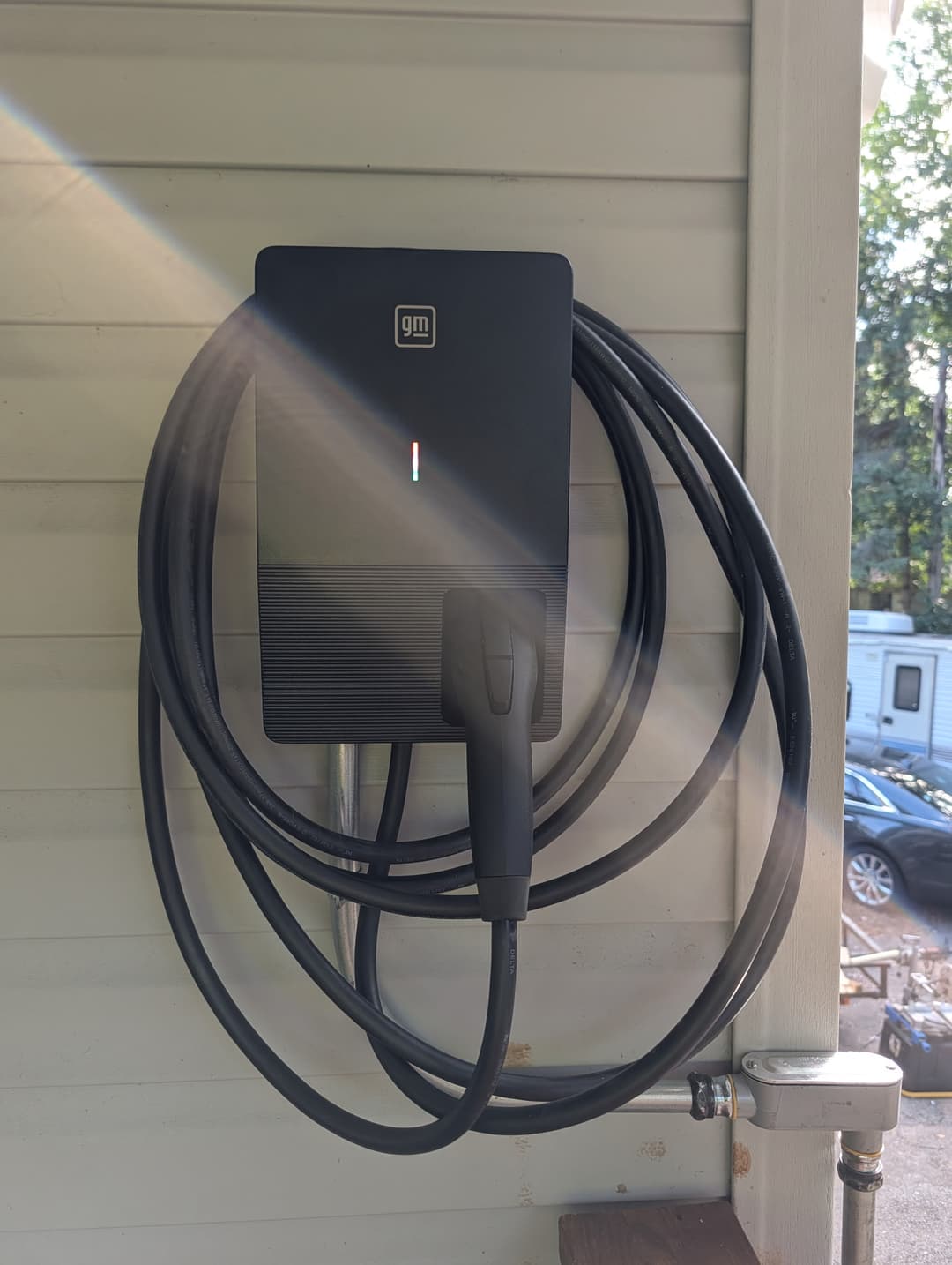 Close-up of a GM Energy EV charger with charging cable coiled on its mounting bracket.