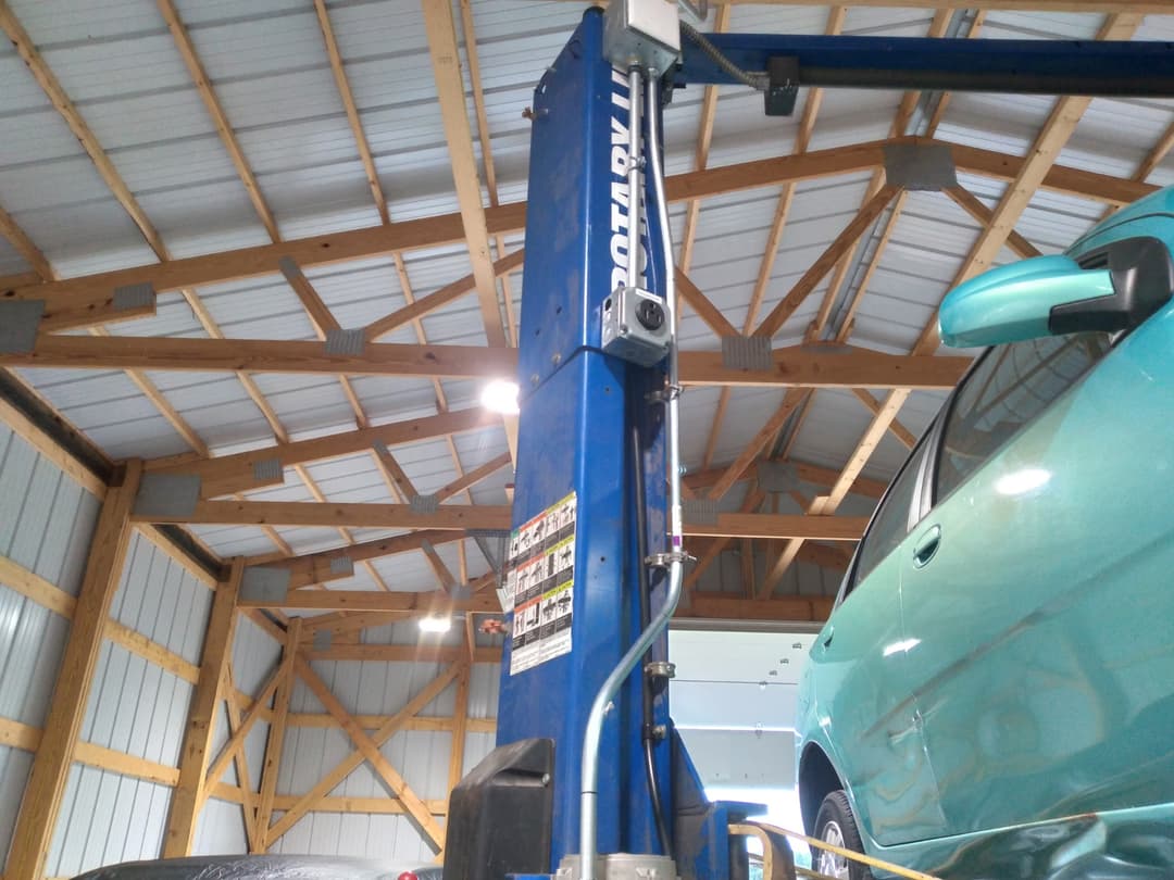 Electrical junction box and outlet wired to a two-post vehicle lift inside an auto shop.