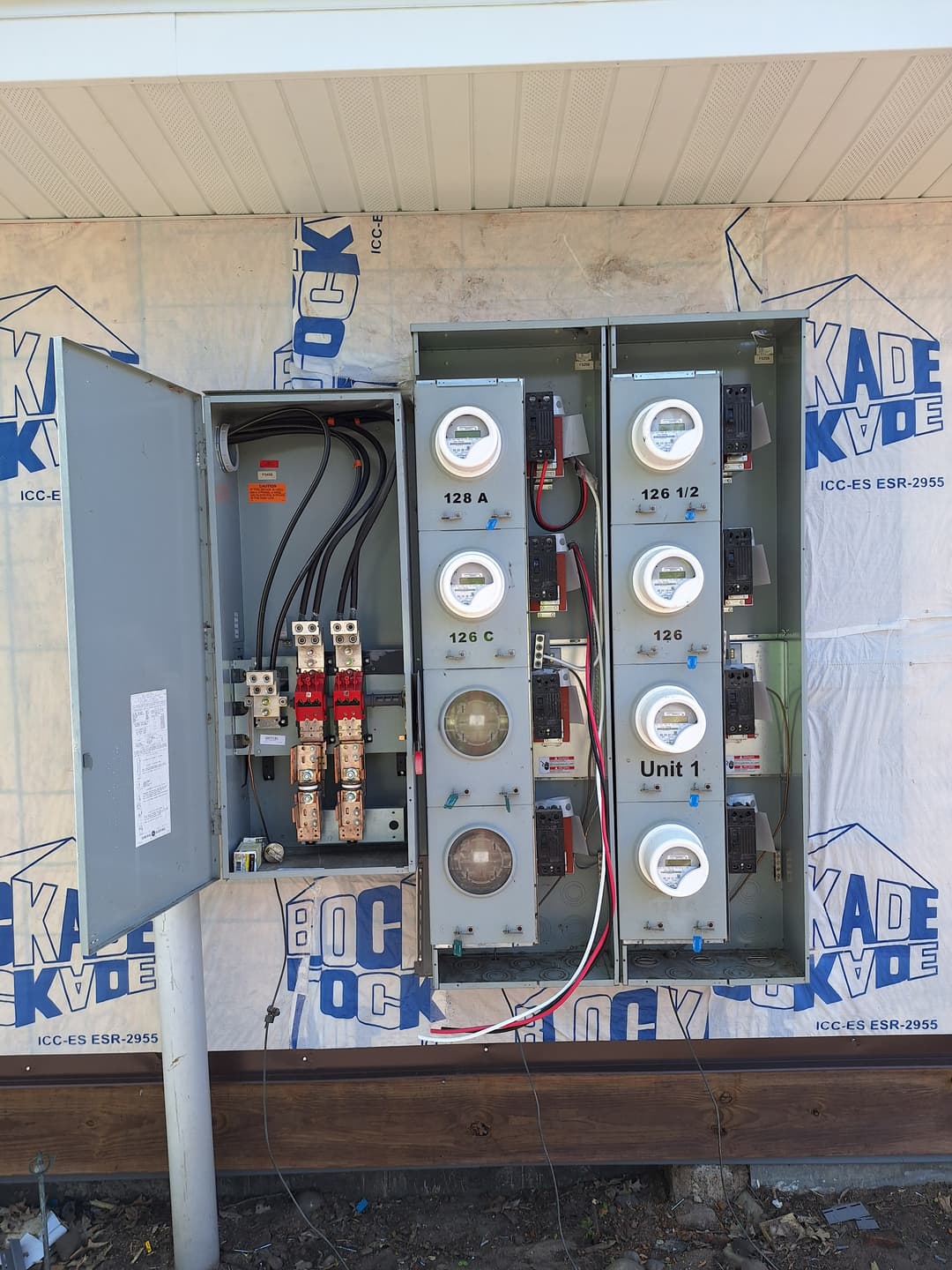 Multi-meter electrical panel with open service compartments and wiring exposed during installation.